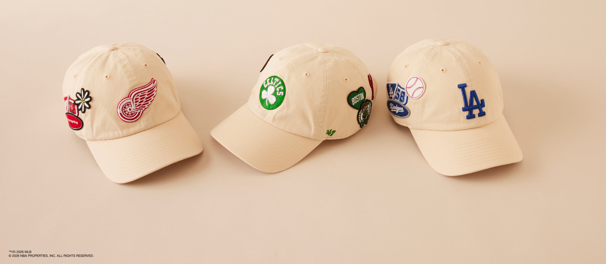 Three baseball caps with different logos on a beige background