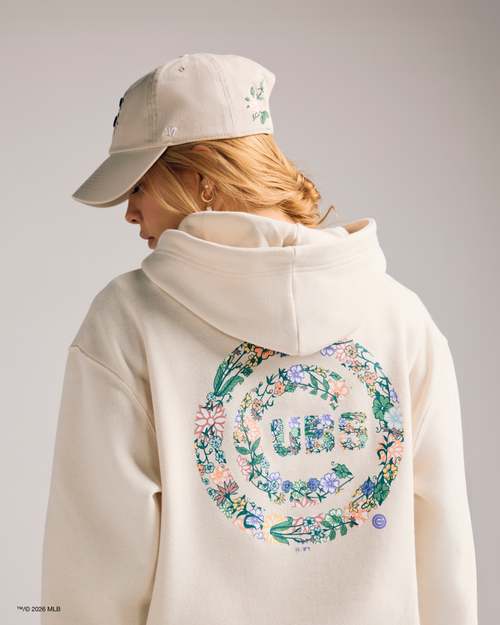 Person wearing a cream hoodie with floral designs and text, standing against a plain background